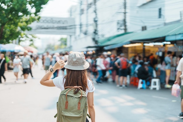 Woman traveler visiting in Bangkok Tourist with backpack and hat sightseeing in Chatuchak Weekend Market landmark and popular attractions in Bangkok Thailand Travel in Southeast Asia concept