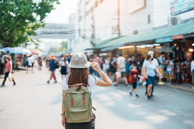 Woman traveler visiting in Bangkok Tourist with backpack and hat sightseeing in Chatuchak Weekend Market landmark and popular attractions in Bangkok Thailand Travel in Southeast Asia concept