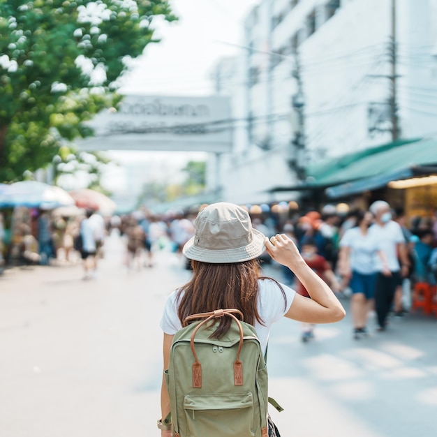 Woman traveler visiting in Bangkok Tourist with backpack and hat sightseeing in Chatuchak Weekend Market landmark and popular attractions in Bangkok Thailand Travel in Southeast Asia concept