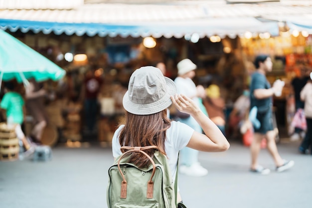 Woman traveler visiting in Bangkok Tourist with backpack and hat sightseeing in Chatuchak Weekend Market landmark and popular attractions in Bangkok Thailand Travel in Southeast Asia concept