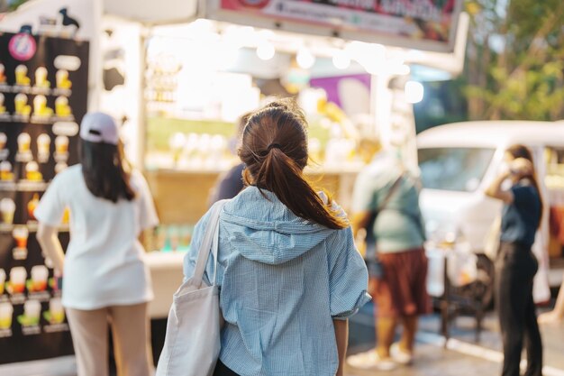 Woman traveler visiting in Food Truck Market Tourist with bag sightseeing in Weekend Market street