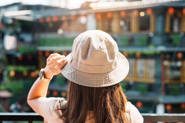 Woman traveler visiting in Taiwan Tourist with hat and backpack sightseeing in Jiufen Old Street village with Tea House background landmark and popular attractions near Taipei city Travel concept