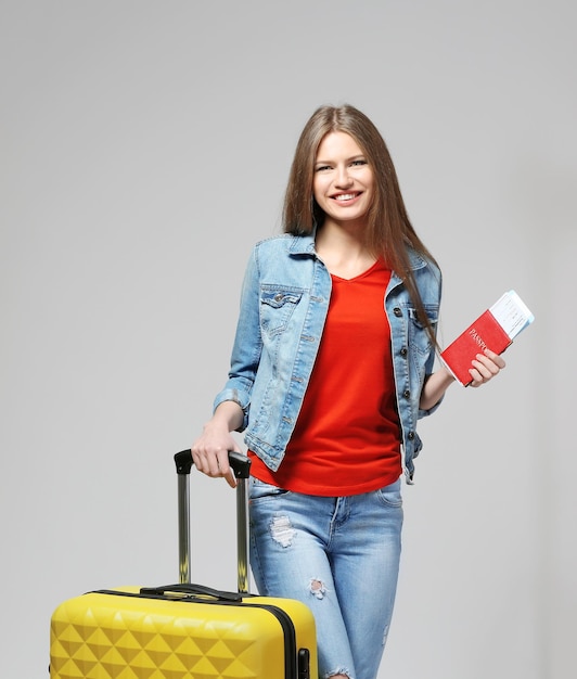 Woman traveler with passport and ticket on color background