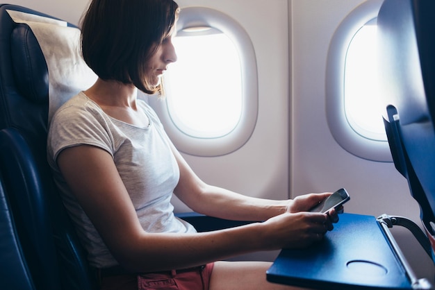 Woman traveling by plane Girl with a phone in her hands sitting on the airplane