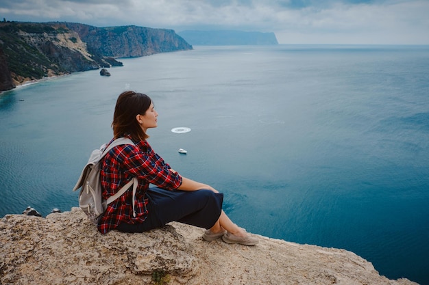 Woman traveling with backpack tourist on seashore in summer