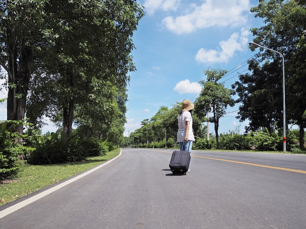 Woman traveller walking alone with luggage along the street 