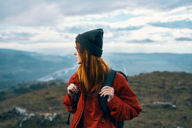 woman travels in the mountains landscape backpack red jacket and hat model High quality photo