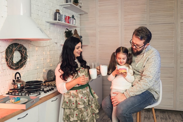 A woman treats her daughter and husband with tea and donuts