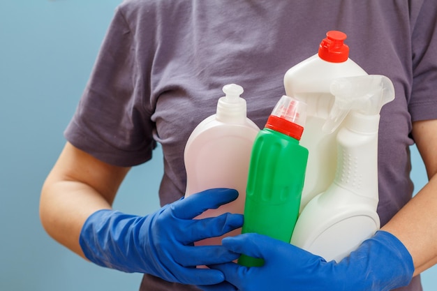 Woman in a tshirt holding plastic bottles of washing liquid on the blue background