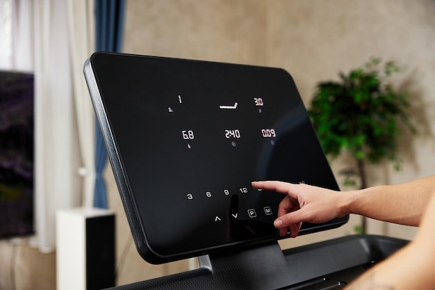 Woman tunes treadmill pressing keys on control panel