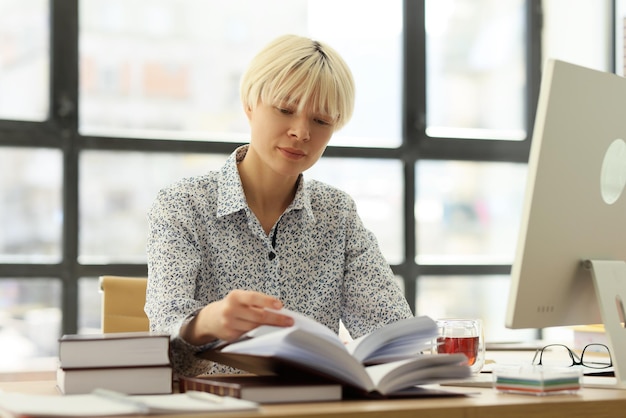 Woman turns pages of work diary sitting at desk in company office manager checkup schedule at