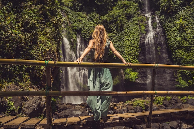 Woman in turquoise dress at the Sekumpul waterfalls in jungles on Bali island Indonesia Bali Travel Concept