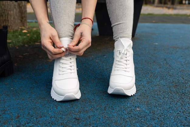 A woman tying her shoes on a blue ground.