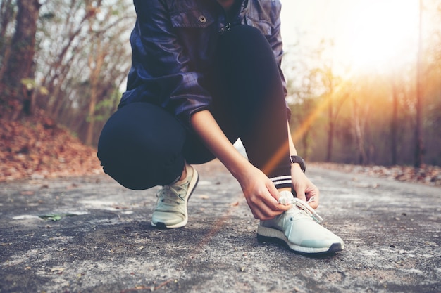 Photo woman tying shoe laces for sport fitness runner getting ready for jogging outdoors