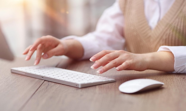 Woman typing on keyboard while sitting at table in modern office