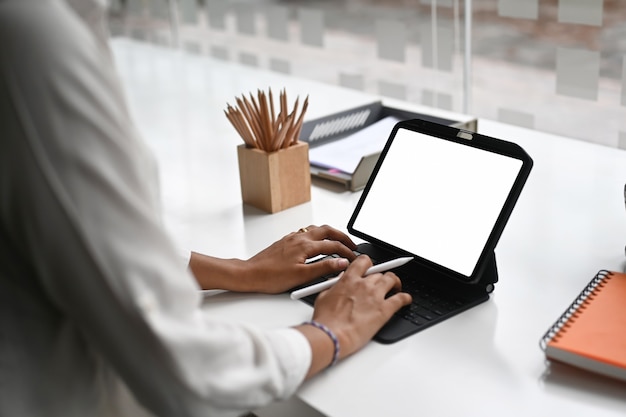 Woman typing on a mockup tablet computer with blank screen