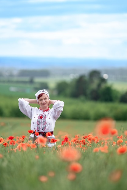 Woman in ukrainian national dress on a flowering poppy field