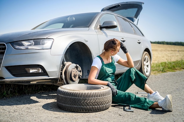 Woman in uniform working for car brake maintenance. Car repair. Safety work