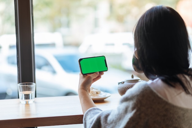 Woman unlocking smartphone screen, place for ad, alpha channel, technologies. Phone with Greenscreen and Chroma Key. Chromakey Mock Up with Tracking Markers and Alpha Matte.