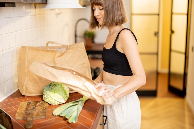 Woman unpacks freshly bought vegetables on kitchen table