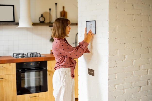 Woman use a digital tablet to control temperature in apartment