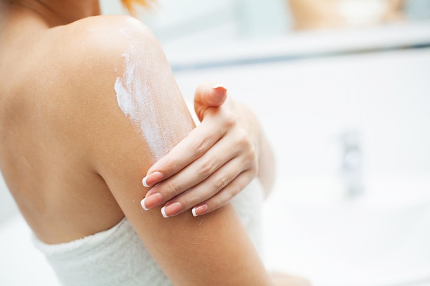 Woman use skin care products at home in light bathroom