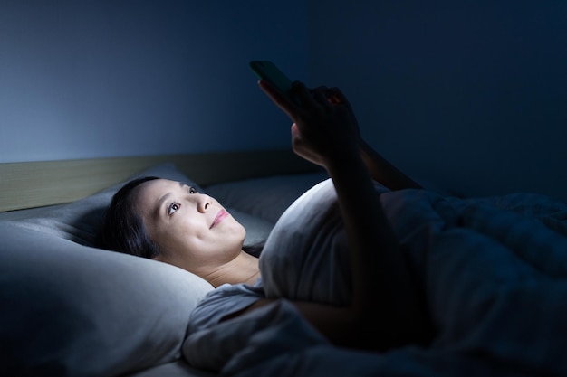 Woman use of smart phone and lying on bed