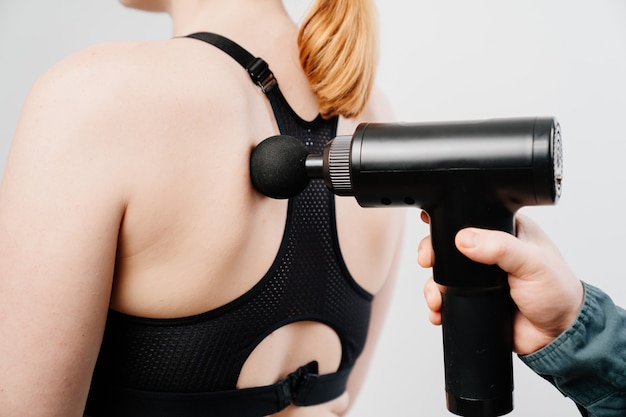 Woman uses massage gun.