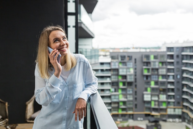  woman uses a mobile phone while standing on the balcony