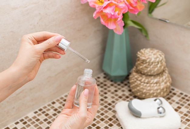 Woman using beauty serum in bathroom Facial treatment