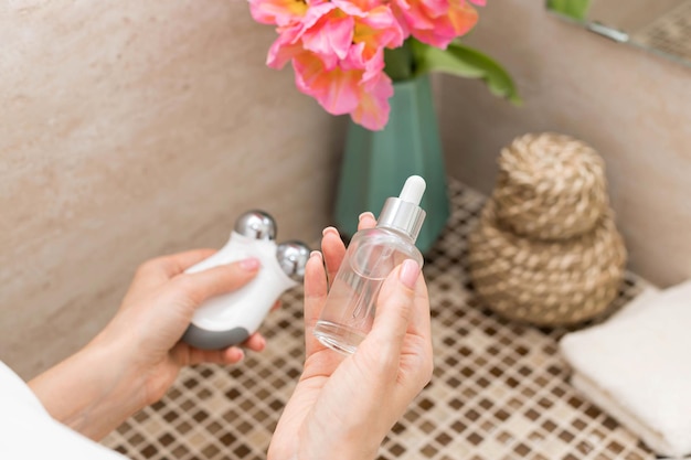 Woman using beauty serum and microcurrent facial toning device