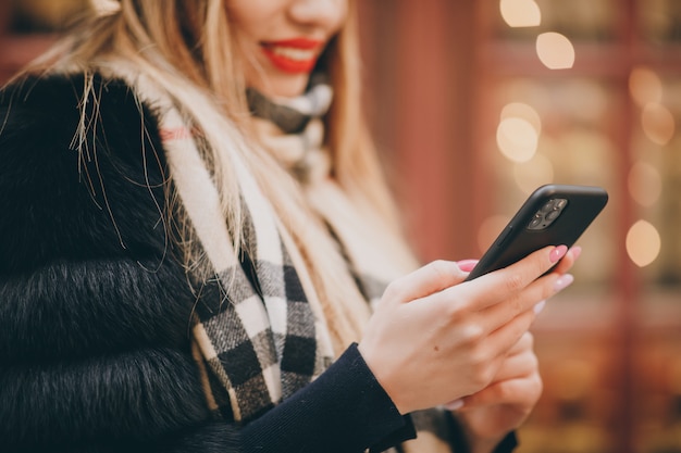 Woman using cell phone in cold weather outside in urban streets