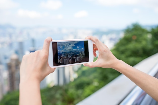 Woman using cellphone to take photo of Hong Kong city