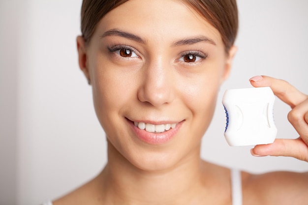 Woman using dental floss for cleaning her teeth