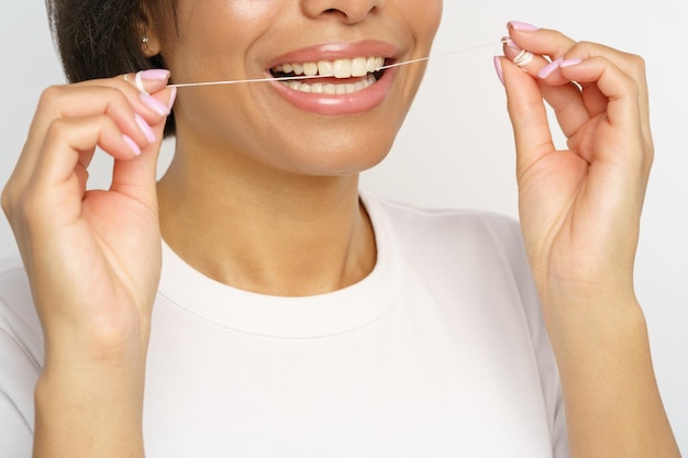 Woman using dental floss cleaning teeth after food female flossing tooth oral hygiene and habits