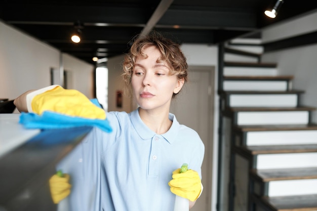 Woman using detergent to wipe dust