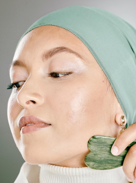 Woman using a facial stone on her face Beauty model doing her morning skin care routine with a jade stone Young female using a gua sha product for healthy skin