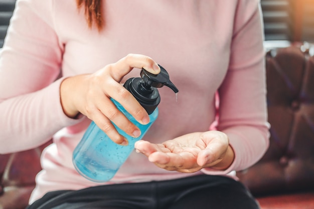 Woman using a hand sanitizer alcohol gel to wash hands to prevent viruses and diseases at home