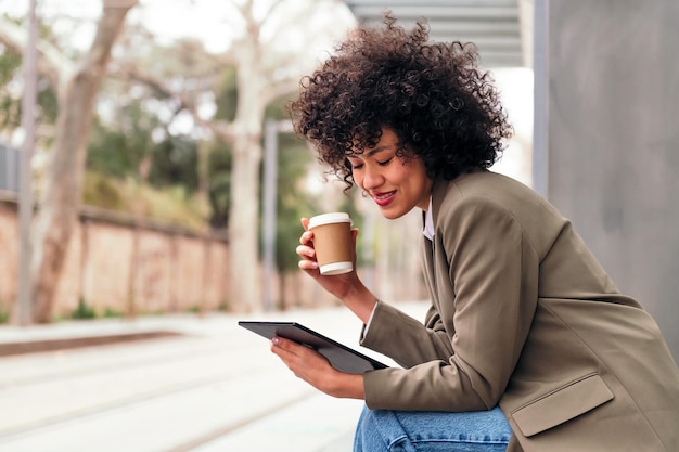 Woman using her tablet while waiting for the bus