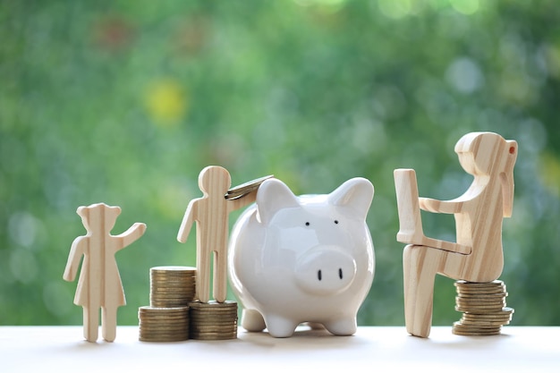 Woman using laptop computer and piggy banks with stack of coin money on natural green background