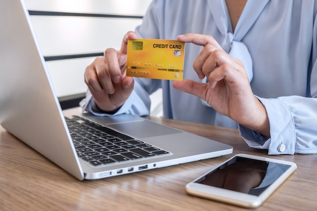 Woman using laptop and holding credit card for paying