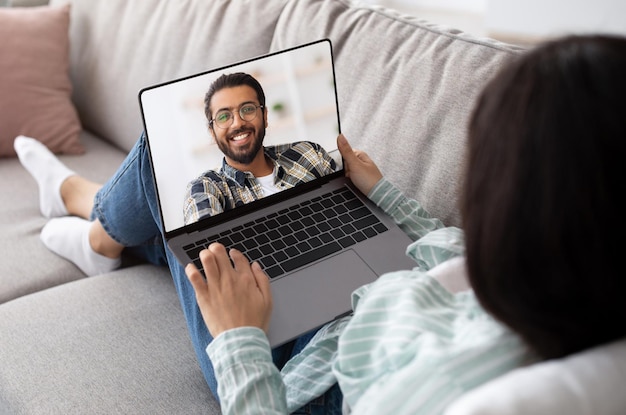 Woman using laptop at home for video chat with her indian boyfriend