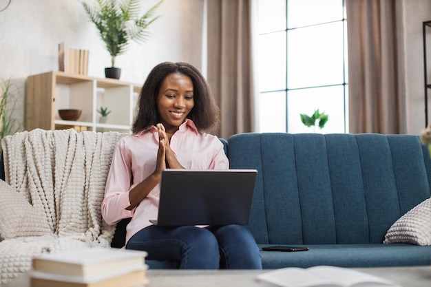 Woman using laptop for video call while sitting on sofa