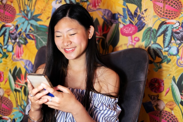 Woman using a mobile phone sitting in an armchair