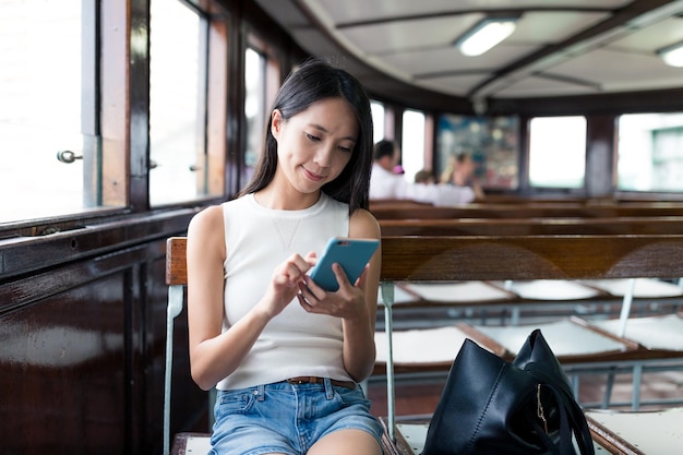 Woman using mobile phone and taking ferry in Hong Kong