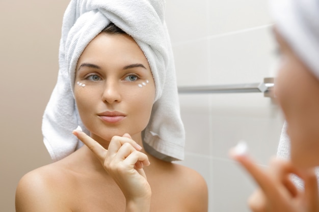 Woman using moisturizing and anti-aging cream under her eyes