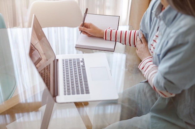 Woman using notebook and taking notes at home