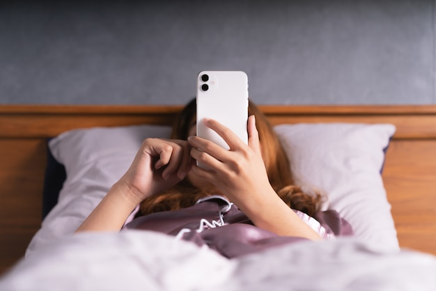 Woman using phone on bed after wake up