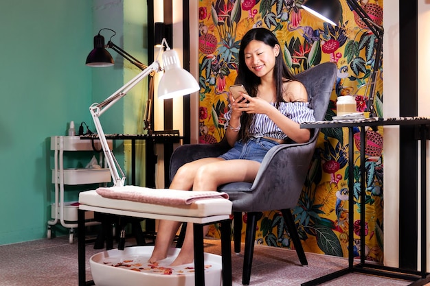 Woman using phone during her pedicure treatment