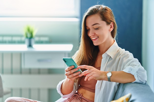 Woman using phone while resting on a sofa